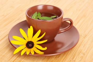 Cup of green tea on the saucer with yellow flower