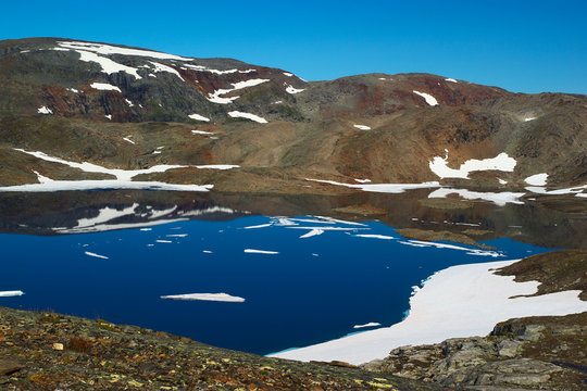 Lake in barren and partly snowcovered mountain scenery