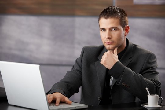 Goodlooking manager sitting at desk in office