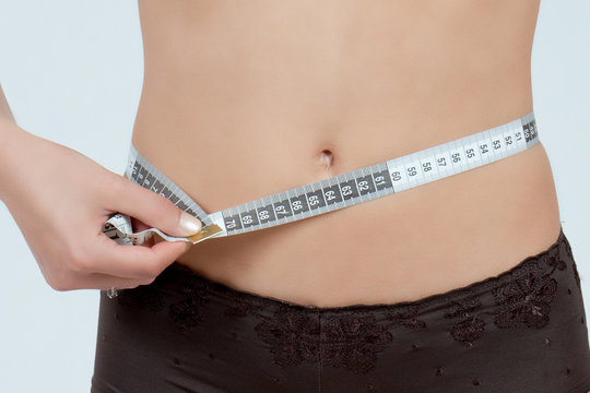 femme mesurant son ventre plat en boxer marron