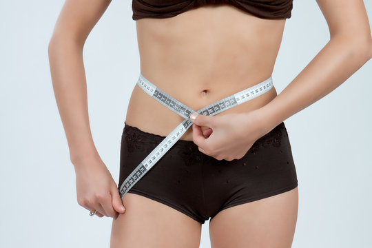 femme mesurant son ventre plat en boxer marron