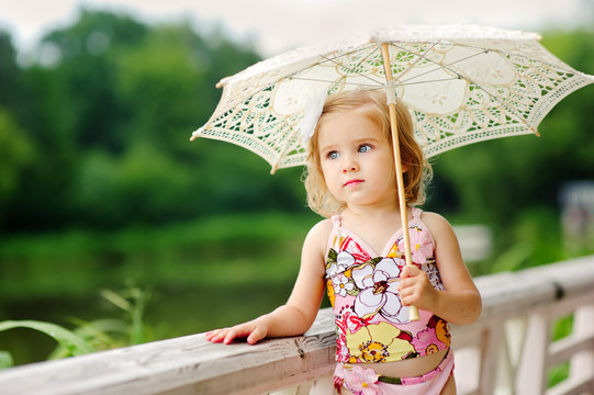 adorable little girl in swimsuit with sun umbrella in the park