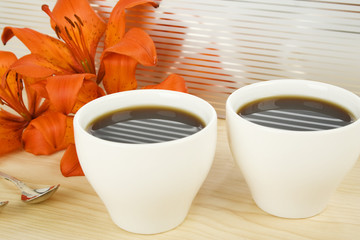 Two cups of espresso and flowers tiger lilies
