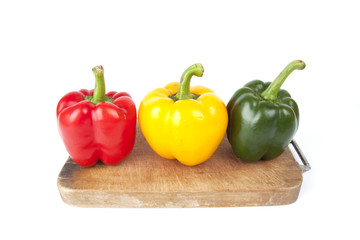 bell pepper, three colors of bell peppers on a wood block.