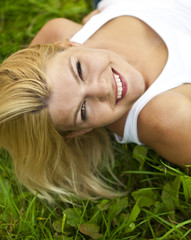 Naklejka premium Pretty blonde girl relaxing outdoor in green grass