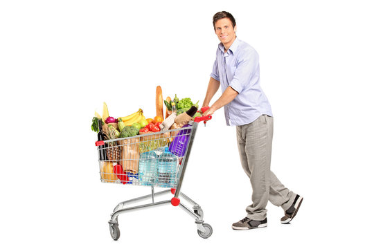 Young male pushing a shopping cart full with groceries