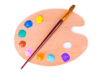 wooden art palette with blobs of paint and a brush on white back