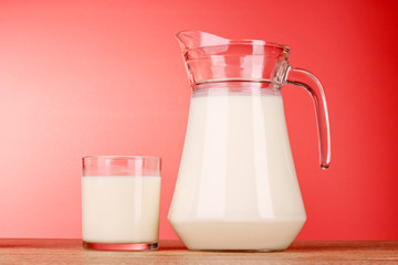 Pitcher and Glass with milk on red background