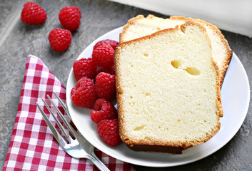 Two sliced fresh pound cake with raspberries.