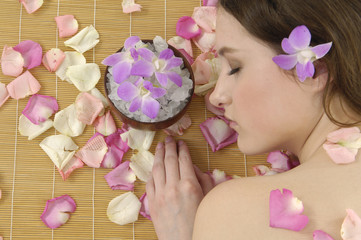 Obraz na płótnie Canvas Beautiful sleeping girl in rose petal with bowl of salt