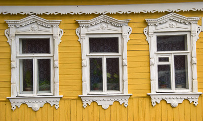 Деревянные окна и резные наличники на фасаде дома