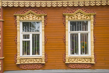 Fototapeta na wymiar Деревянные окна и резные наличники на фасаде дома