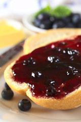 Blueberry jam on half a bun with butter and blueberries