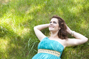 Naklejka na ściany i meble Pretty girl relaxing outdoor in green grass