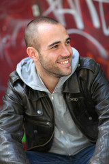 Obraz premium Smiling young man sitting in street