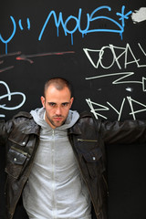 Portrait of bad boy standing on tagged wall