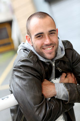 Smiling young man with leather jacket in town