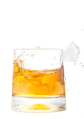 glass of whiskey with ice cubes splashing out over white