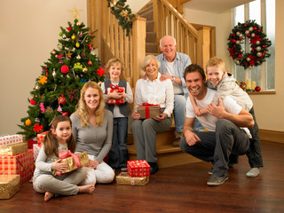 Family with gifts in front of Christmas tree