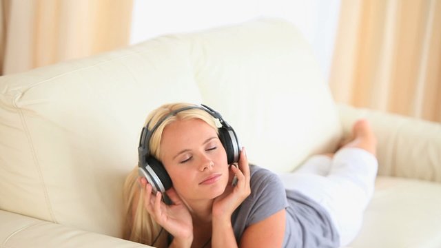 Woman lying on a sofa enjoying hearing music