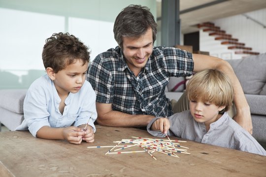 Boys playing pick up sticks with their father