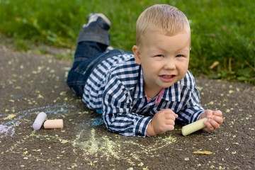 Boy drawing with chalk on the asphalt