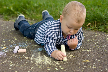 Boy drawing with chalk on the asphalt