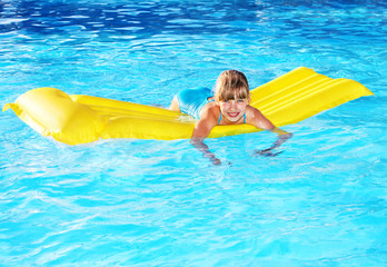 Child swimming on inflatable beach mattress.