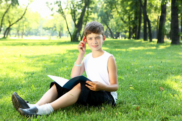 Naklejka na ściany i meble Portrait of a boy with a book in the park