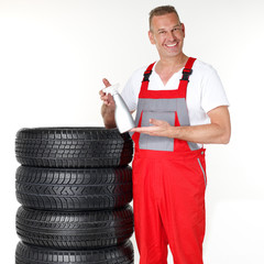 Motor mechanic next to a set of winter tyres holding a bottle