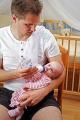father bottle-feeding his daughter