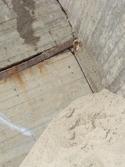 large pile of sand in front of an industrial concrete wall