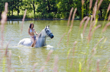 equestrian on horseback riding through water
