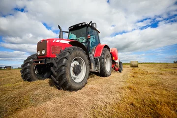 Fototapete Traktor Traktor sammelt Heuhaufen auf dem Feld