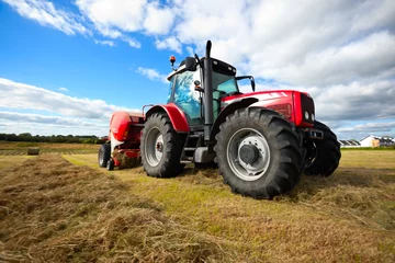 Foto op Plexiglas Tractor tractor die hooiberg in het veld verzamelt