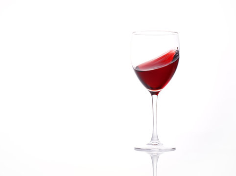 Isolated and moving red wine glass over a white background