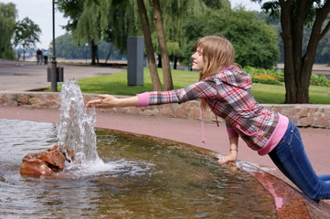 Юная девушка в парке отдыха у фонтана