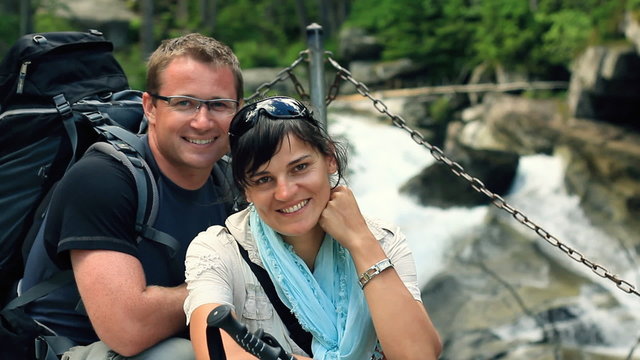 Portrait of happy hikers couple by the stream in the woods