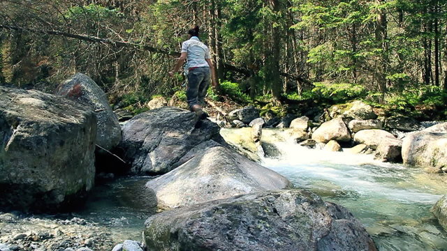 Womun jumping on the rocks in the forest stream, slow motion