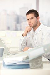 Naklejka premium Young casual office worker sitting at desk