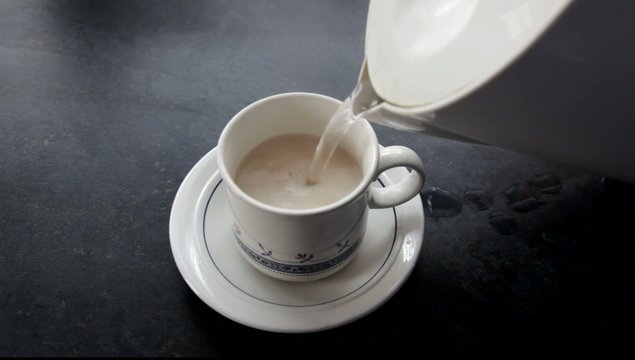 Teacup being filled with boiling water.