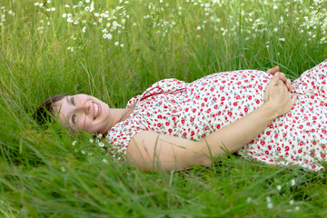 Pregnant woman lie in chamomile