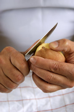 eine Kartoffel wird mit einem Küchenmesser geschält