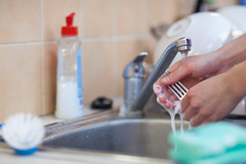 Washing of the dishes - woman hands rinsing dishes