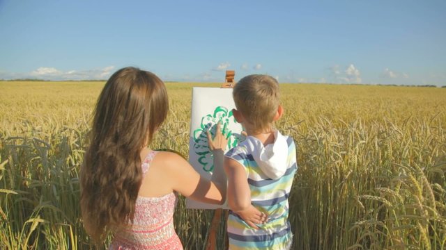 Young woman with boy drawing with fingers in the field