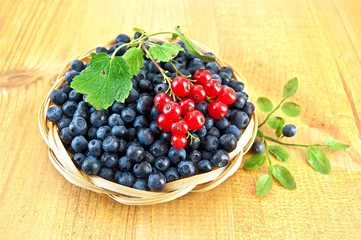 Blueberries with sprigs of red currants on the board
