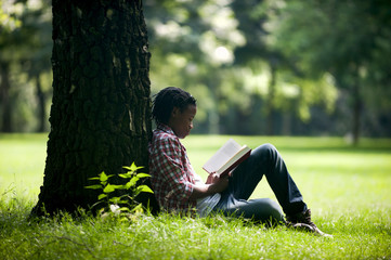 Junge im Park, ließt ein Buch.