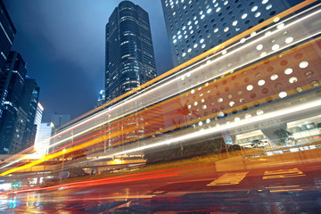 Obraz premium traffic light trails in the street by modern building