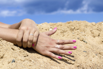 Woman's hands against sand and blue sky