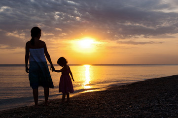Mother and kid on sunset beach